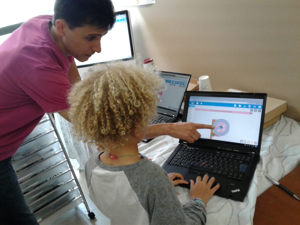 Teacher points to a computer screen, instructing a student about Music Blocks.